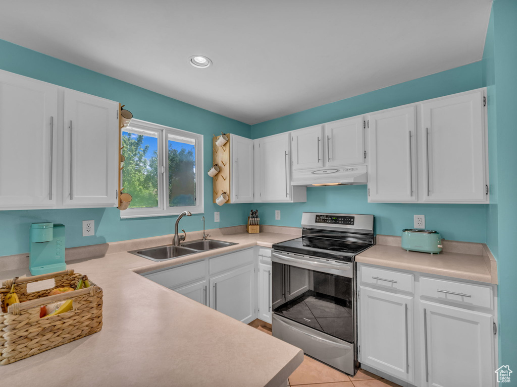 Kitchen with stainless steel electric range oven, a sink, under cabinet range hood, white cabinets, and recessed lighting