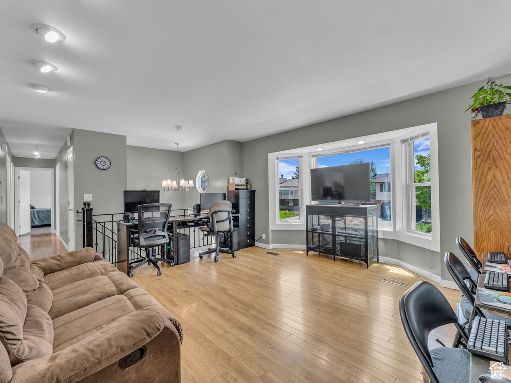 Living room featuring a desk, light wood-style floors, a chandelier, and baseboards