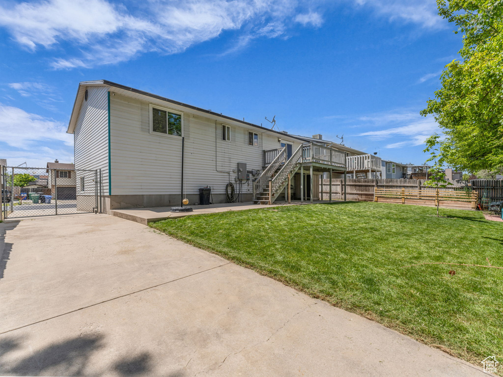Rear view of property featuring stairs, a wooden deck, a gate, and concrete driveway
