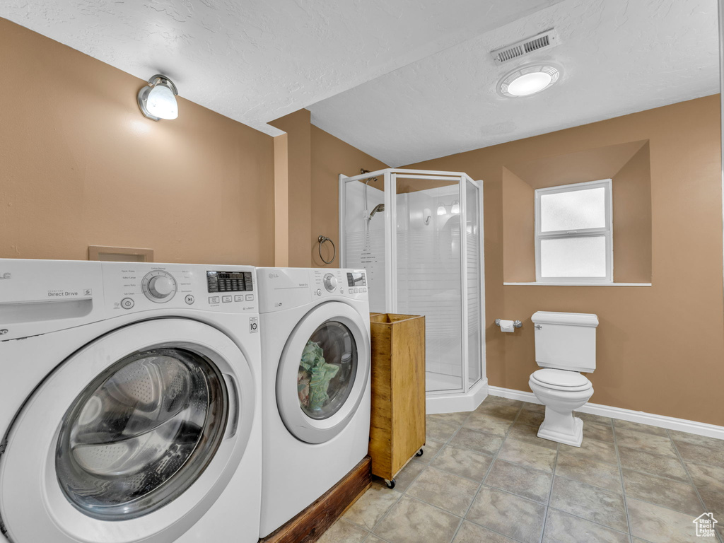 Washroom with separate washer and dryer, baseboards, and a textured ceiling