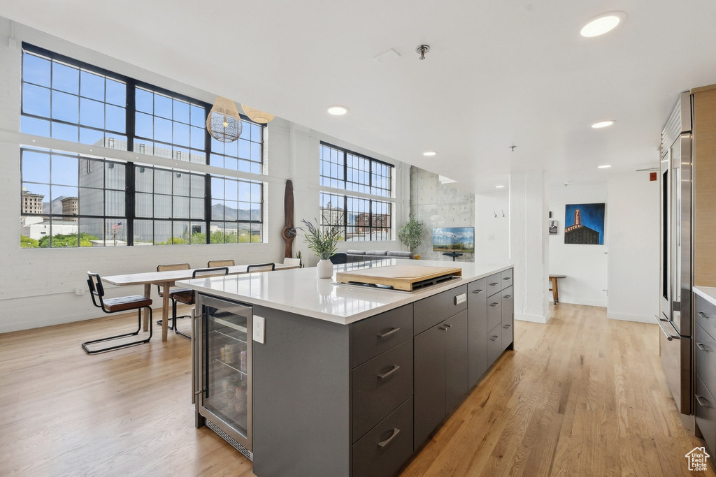 Kitchen with wine cooler, baseboards, light countertops, light wood finished floors, and recessed lighting