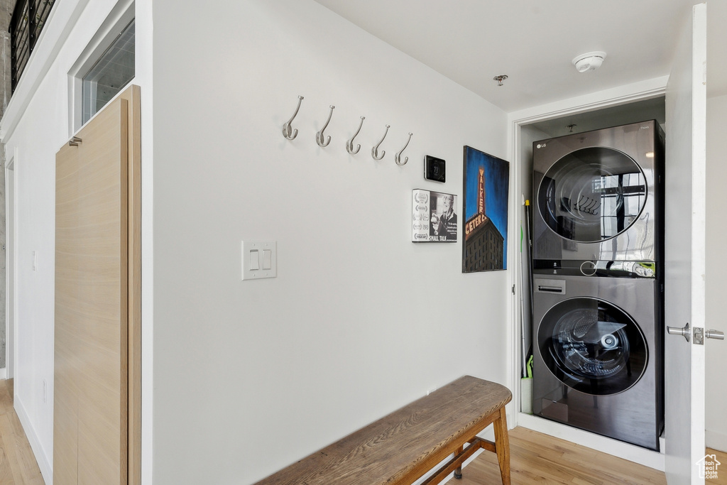 Washroom with stacked washer and clothes dryer and light wood-type flooring