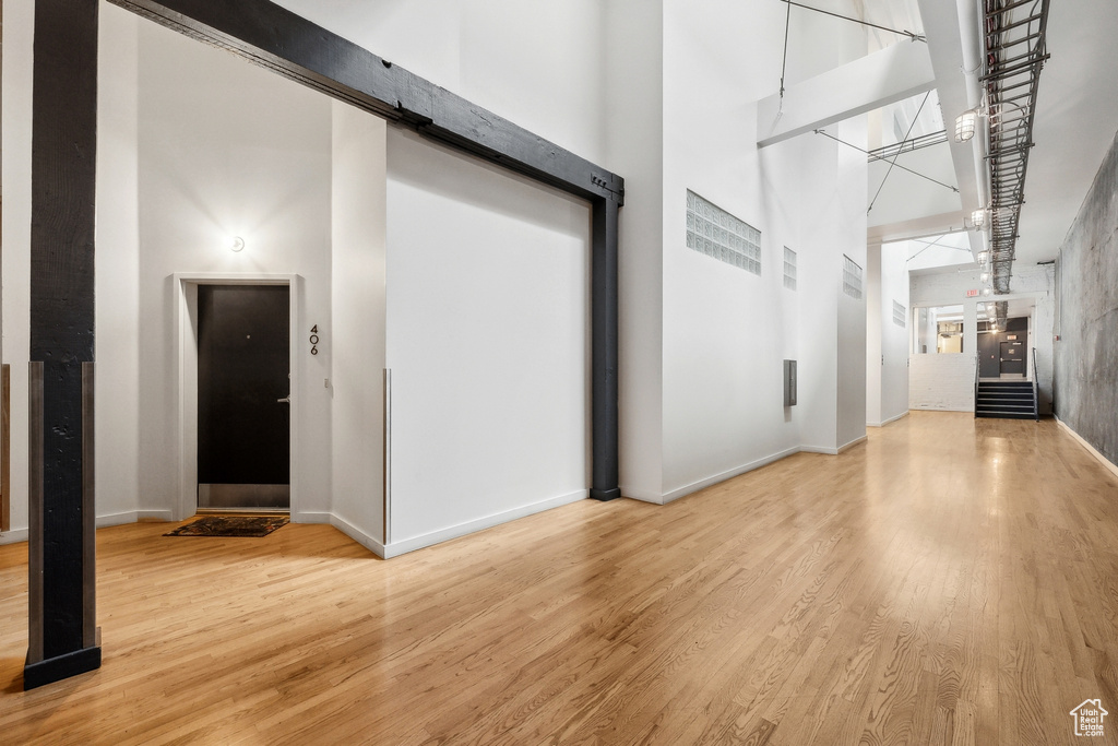 Hallway featuring a high ceiling, light wood finished floors, and baseboards