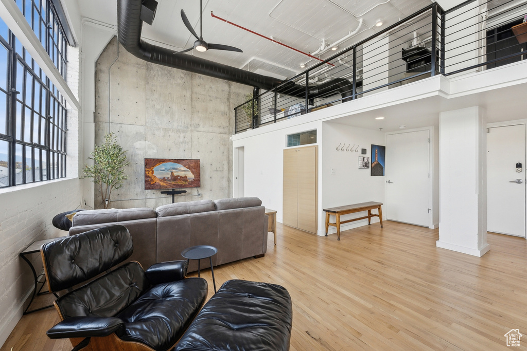 Living area with a high ceiling, a ceiling fan, and wood finished floors