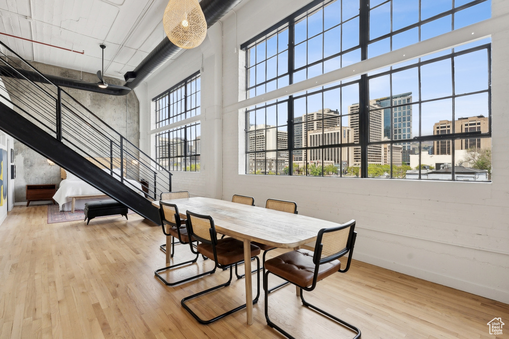 Dining area featuring a high ceiling, wood finished floors, a city view, stairs, and baseboards