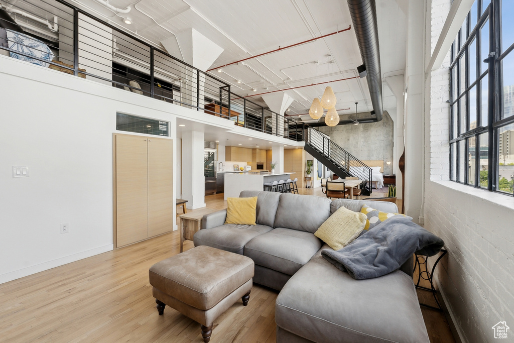 Living area featuring light wood-style floors, a high ceiling, and baseboards
