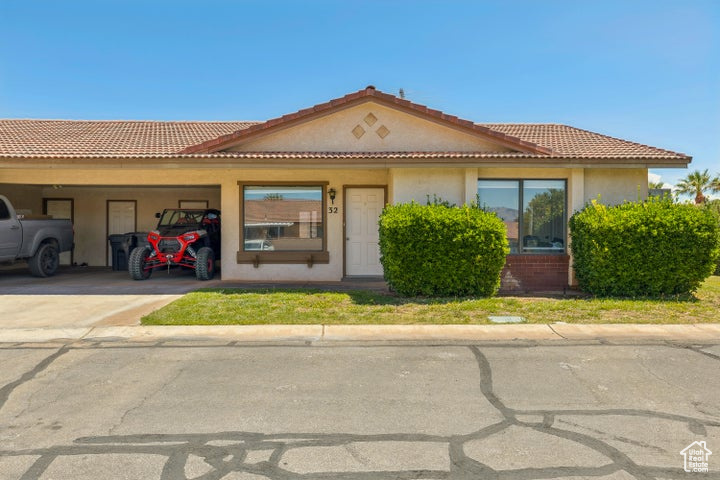 View of front of home with a carport, stucco siding, driveway, and a tile roof