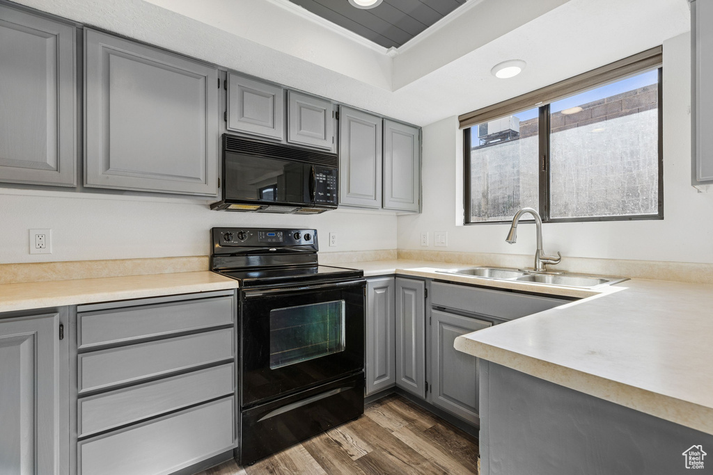 Kitchen with gray cabinets, black appliances, a sink, dark wood-style floors, and light countertops