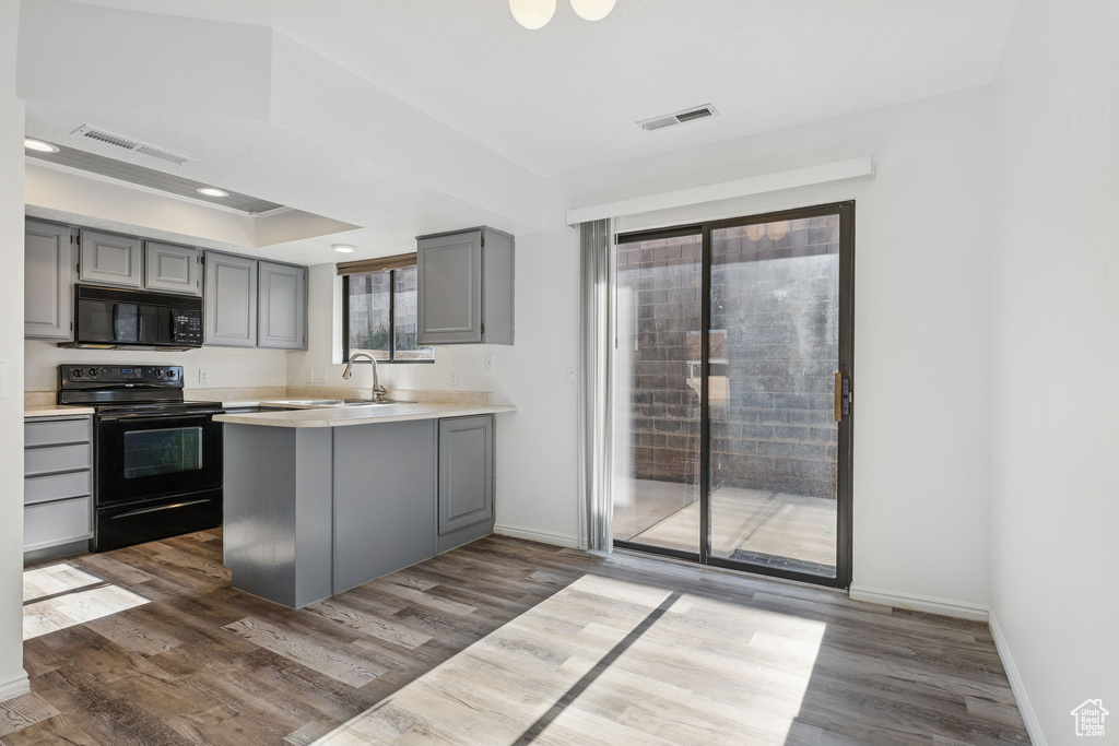 Kitchen featuring black appliances, gray cabinetry, dark wood-style flooring, and recessed lighting