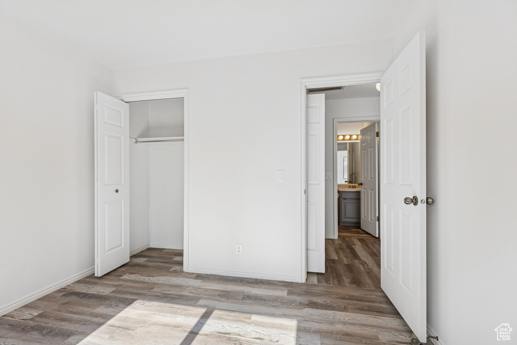 Unfurnished bedroom with wood finished floors, a closet, and baseboards