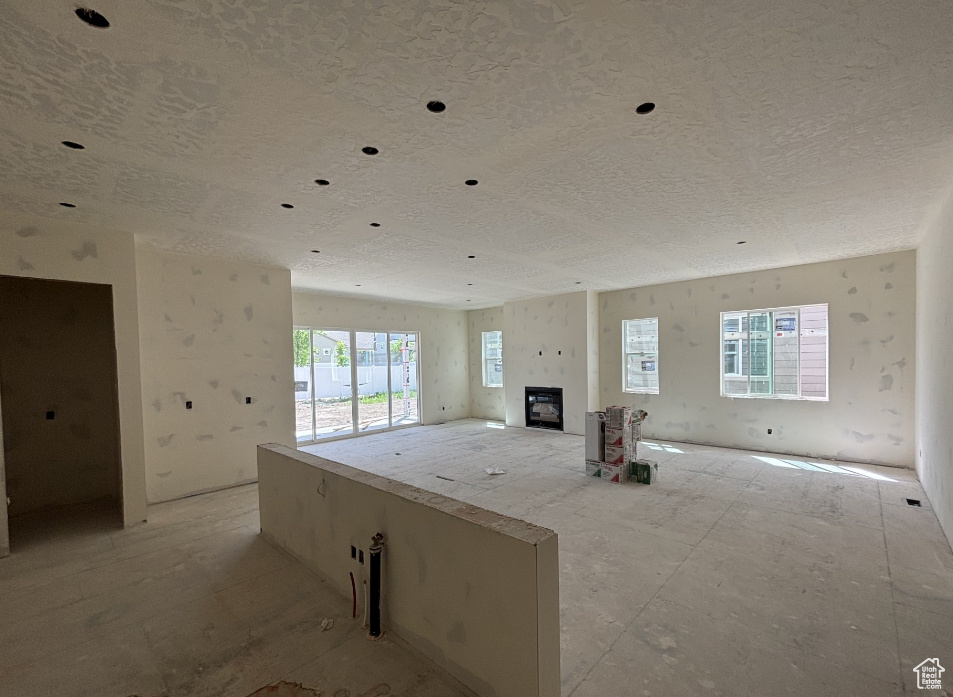 Unfurnished living room featuring a textured ceiling and a glass covered fireplace