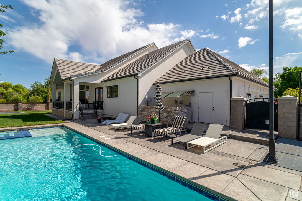 Back of house featuring a patio, a tiled roof, a gate, and stucco siding