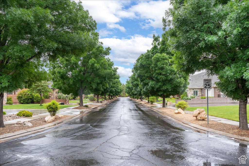 View of asphalt street featuring sidewalks, curbs, and traffic signs