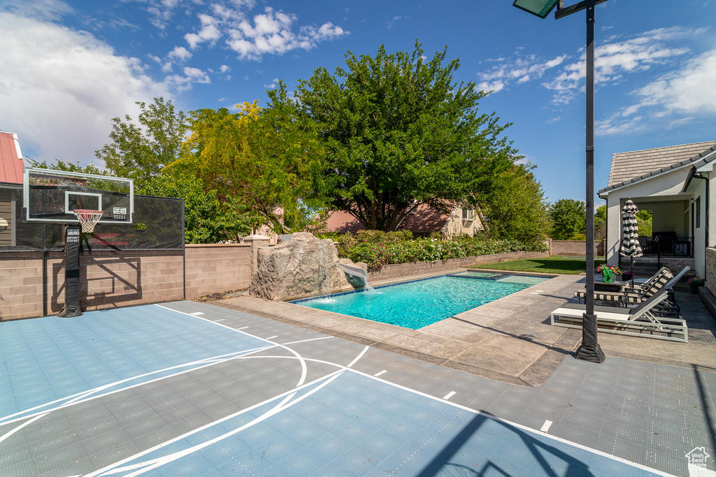 View of basketball court featuring basketball hoop and fence