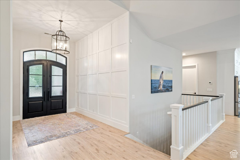 Entrance foyer featuring a chandelier, light wood-style floors, french doors, and baseboards
