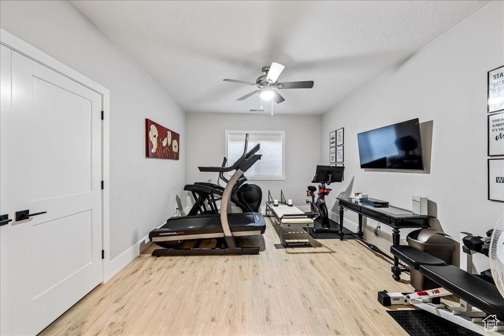 Workout room featuring wood finished floors, a ceiling fan, and baseboards