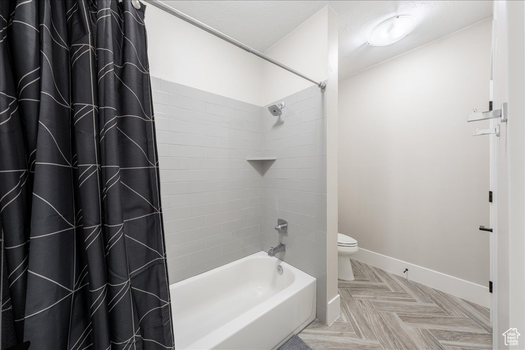 Bathroom with baseboards, toilet, and shower / tub combo with curtain