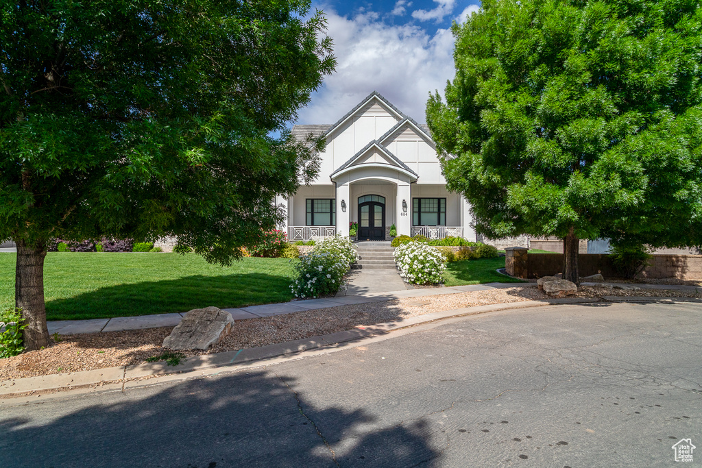 Tudor house with covered porch, a front yard, french doors, and stucco siding