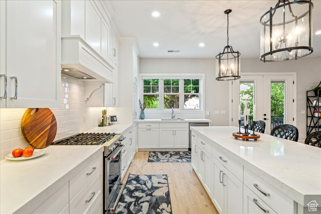 Kitchen with stainless steel appliances, plenty of natural light, light wood-style floors, a chandelier, and recessed lighting
