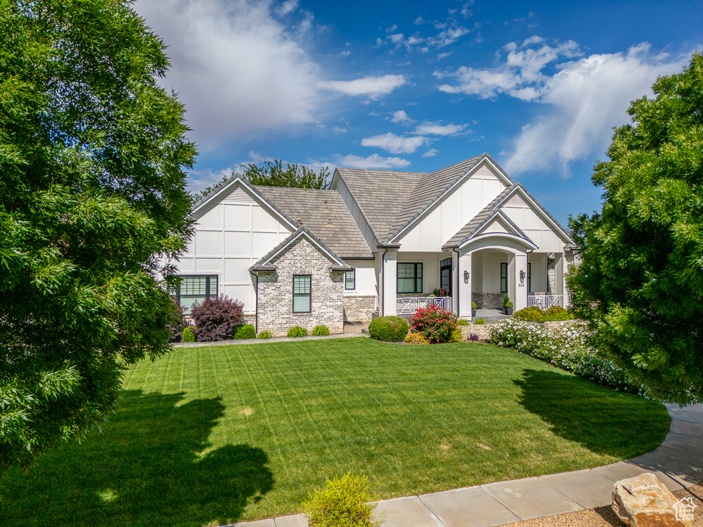 Tudor home with a front yard, stone siding, stucco siding, and a porch