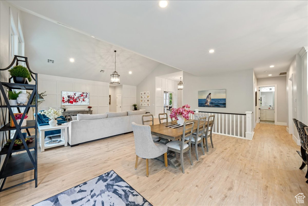 Dining space featuring light wood finished floors, vaulted ceiling, recessed lighting, a chandelier, and baseboards