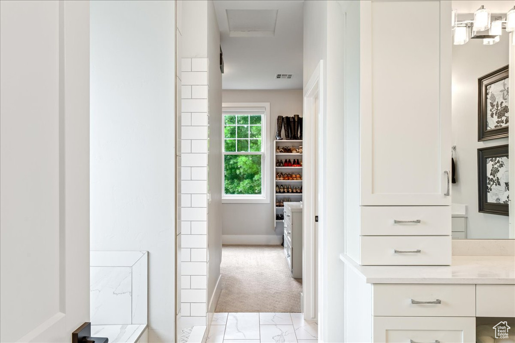 Bathroom featuring vanity, baseboards, marble look tiles, and a shower