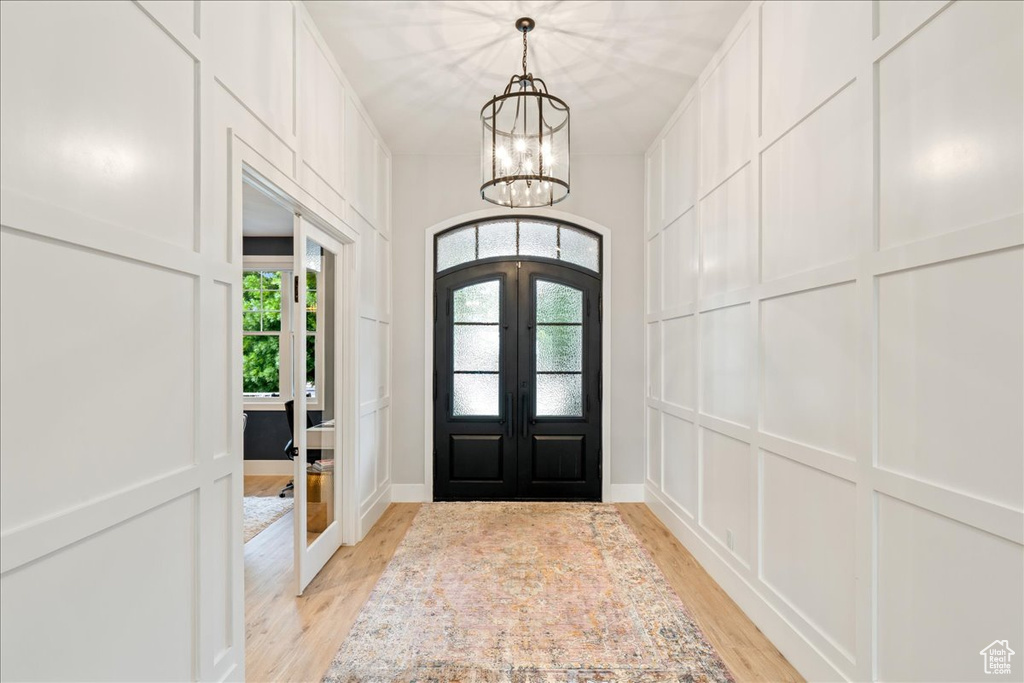 Entryway featuring french doors, light wood-style flooring, and a chandelier