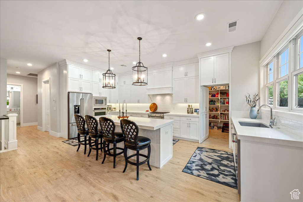 Kitchen featuring a sink, appliances with stainless steel finishes, tasteful backsplash, a kitchen breakfast bar, and recessed lighting
