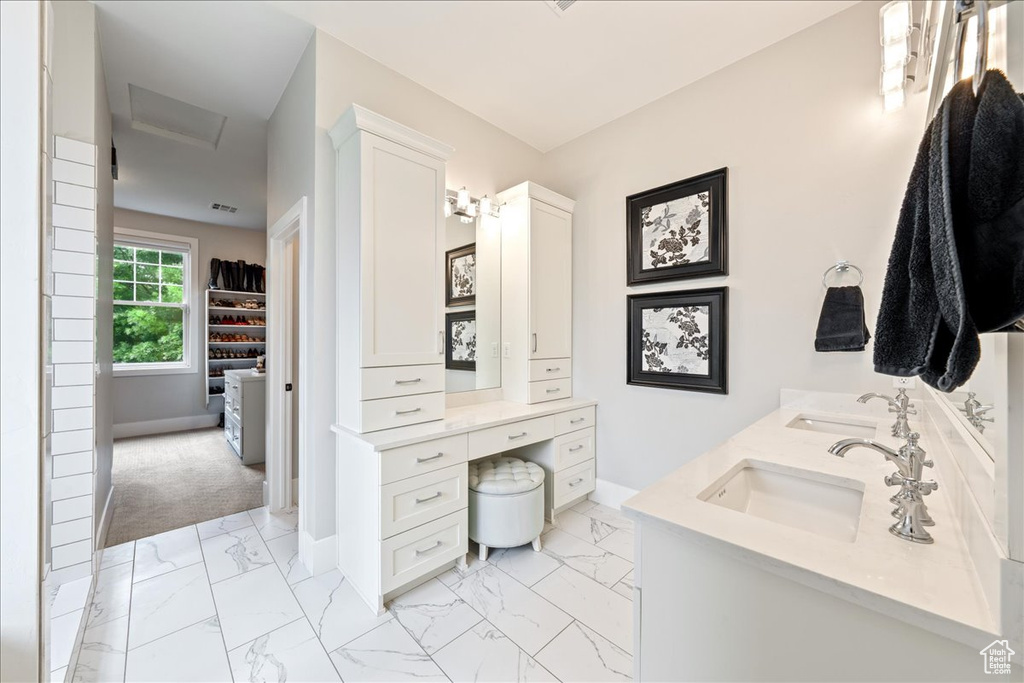 Bathroom featuring marble finish floors, double vanity, and baseboards