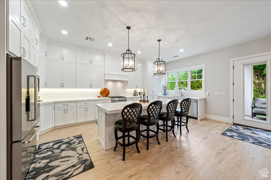 Kitchen featuring appliances with stainless steel finishes, light countertops, recessed lighting, light wood-style flooring, and tasteful backsplash