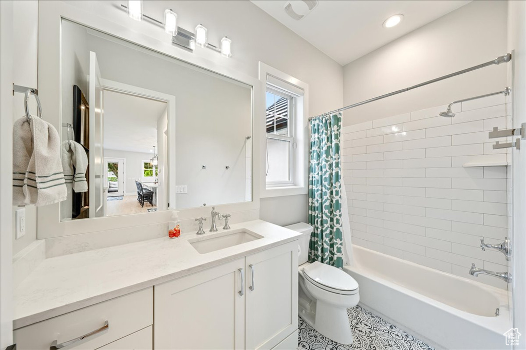 Bathroom with toilet, shower / bathtub combination with curtain, vanity, and tile patterned floors