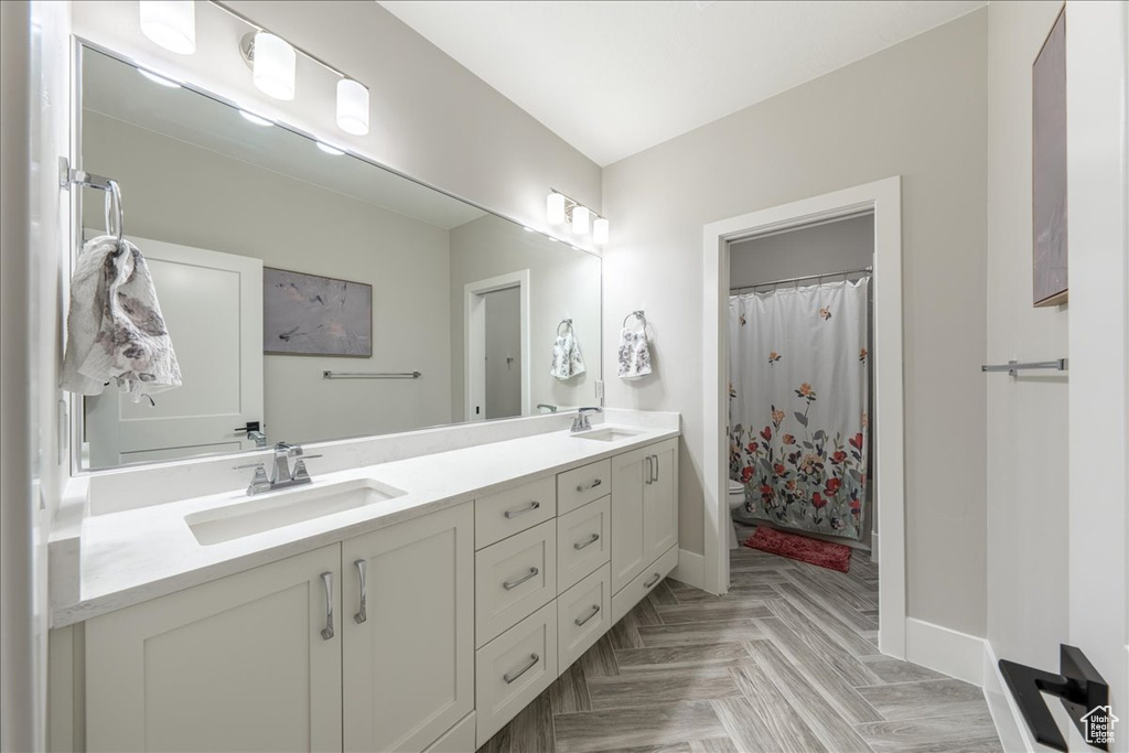 Full bathroom with baseboards, double vanity, toilet, and curtained shower