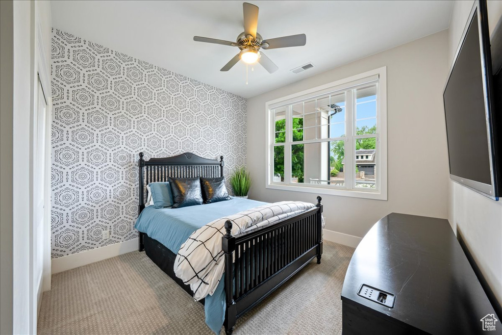 Carpeted bedroom featuring wallpapered walls, baseboards, an accent wall, and a ceiling fan