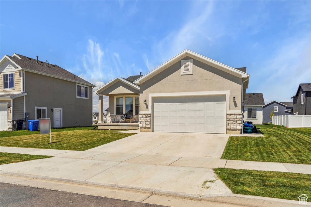 Ranch-style home with stone siding, concrete driveway, an attached garage, and stucco siding