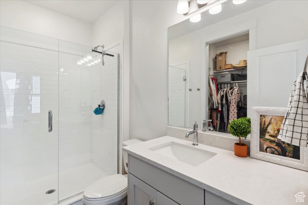 Full bathroom featuring a stall shower, toilet, vanity, and a walk in closet