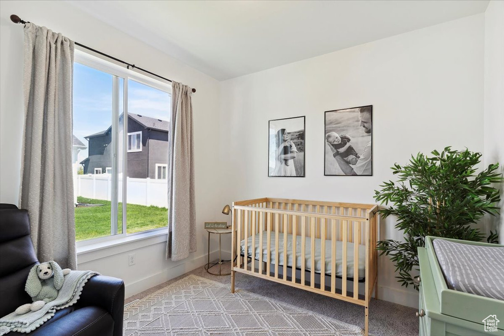Carpeted bedroom featuring baseboards and a nursery area