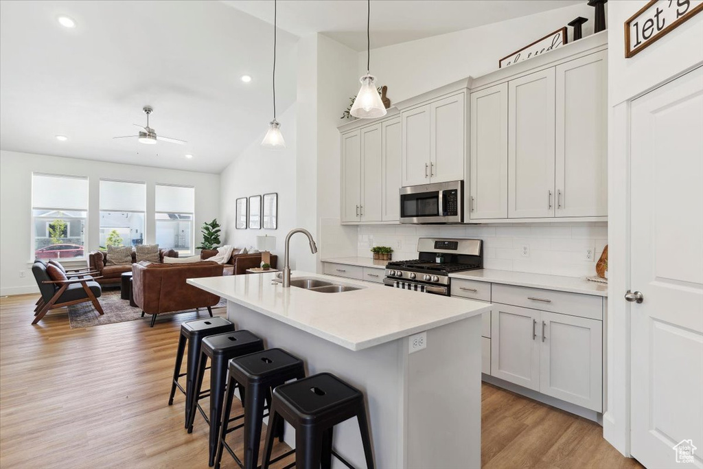 Kitchen featuring stainless steel appliances, a sink, decorative backsplash, a kitchen bar, and lofted ceiling