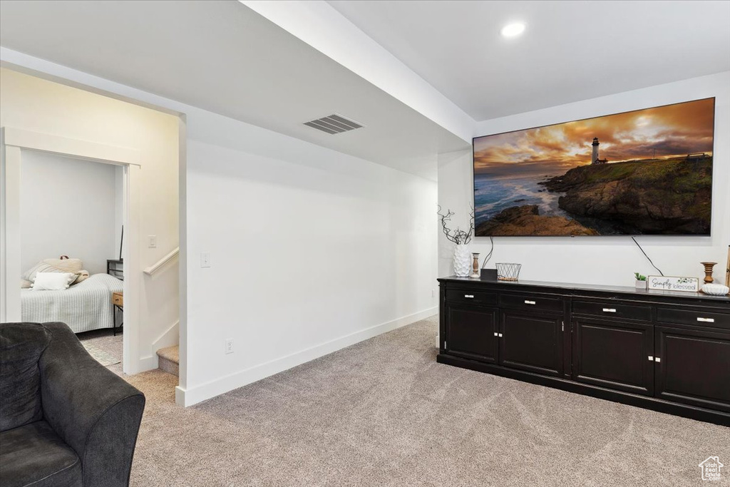 Living area featuring light carpet, baseboards, recessed lighting, and stairs