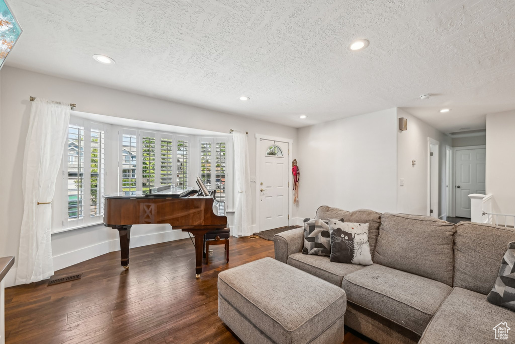 Living room featuring a textured ceiling, dark wood finished floors, recessed lighting, and baseboards