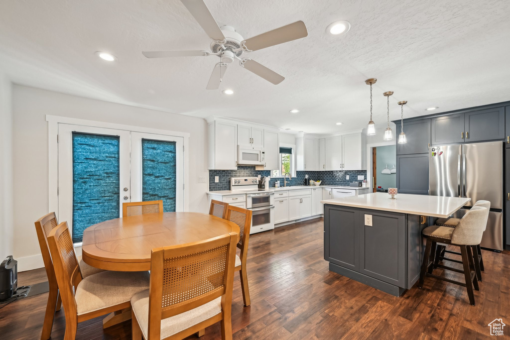 Kitchen with white microwave, range with two ovens, freestanding refrigerator, light countertops, and a kitchen island