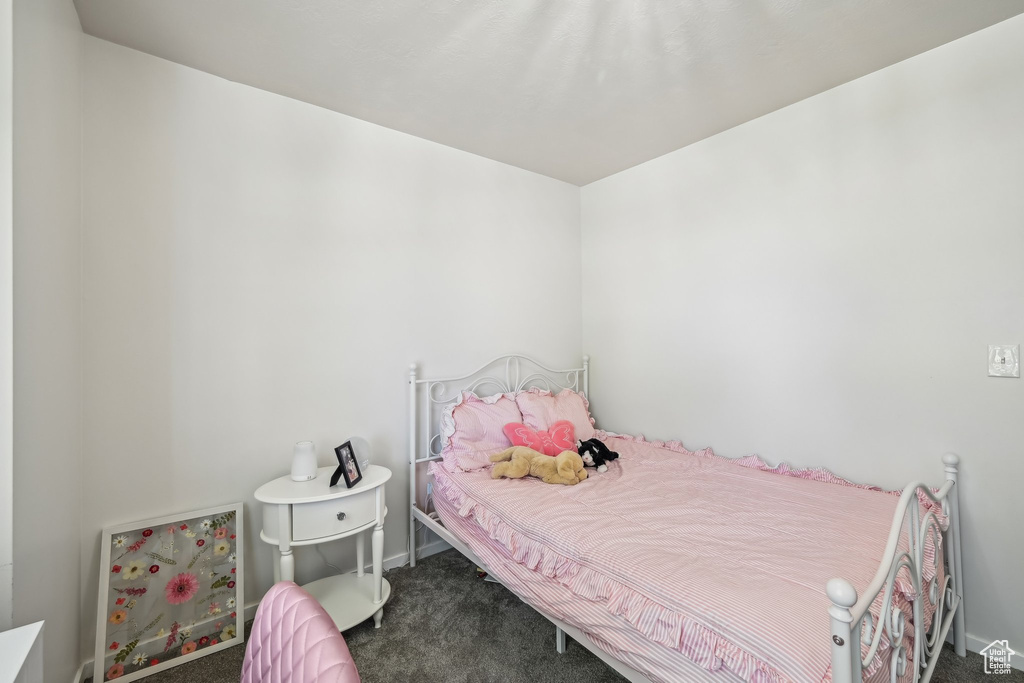Bedroom with dark colored carpet and baseboards