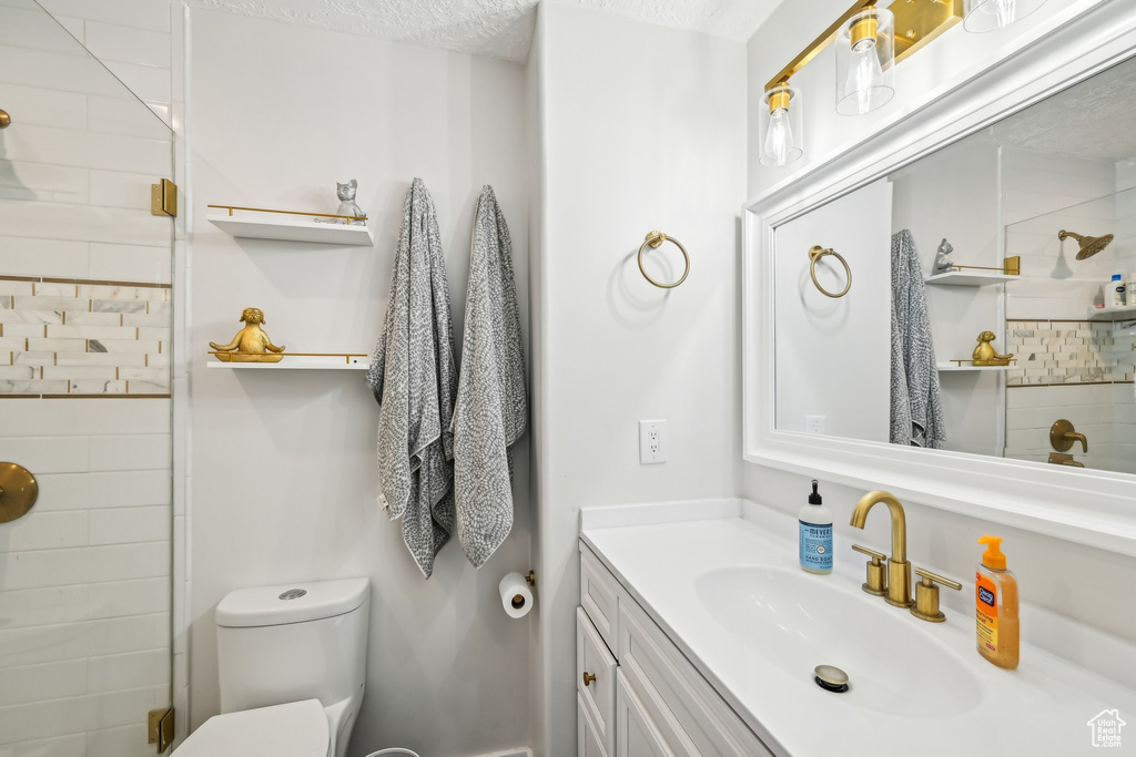 Full bathroom with toilet, vanity, and tiled shower