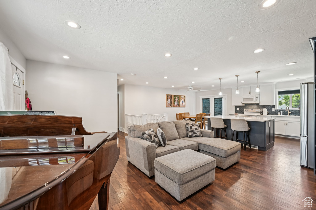Living room with recessed lighting, dark wood-style floors, a textured ceiling, and a ceiling fan