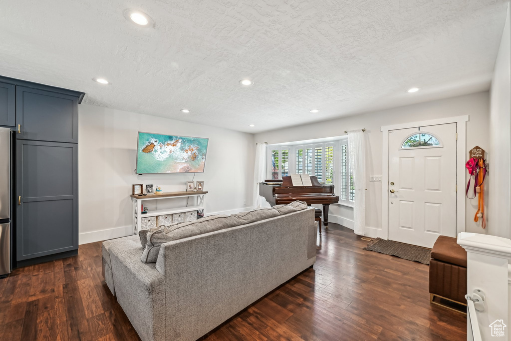 Living room with a textured ceiling, recessed lighting, dark wood-style floors, and baseboards