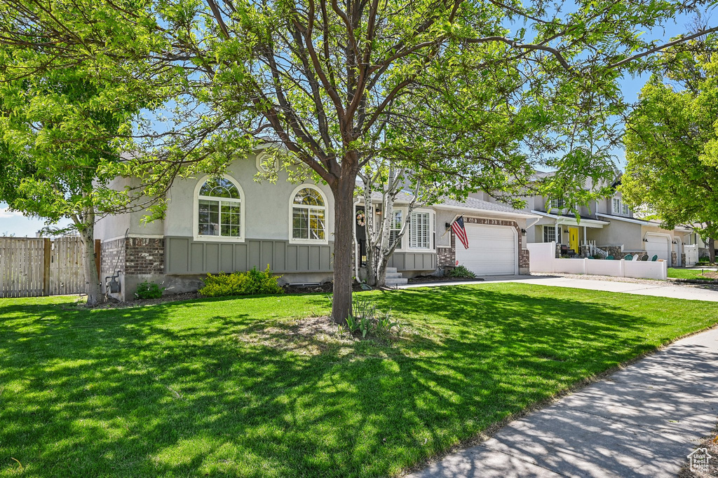 View of front of home with brick siding, an attached garage, driveway, and stucco siding