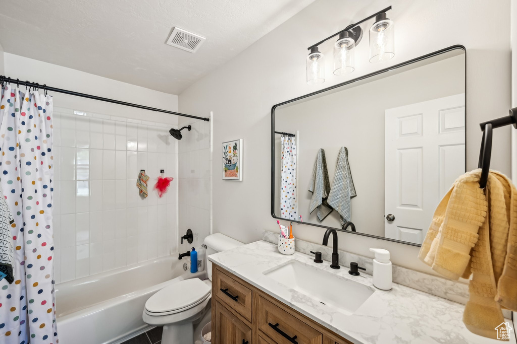 Bathroom featuring toilet, vanity, and shower / bathtub combination with curtain