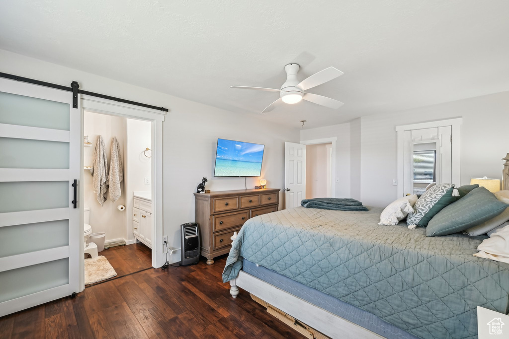 Bedroom featuring dark wood-style flooring, a barn door, ceiling fan, connected bathroom, and baseboards