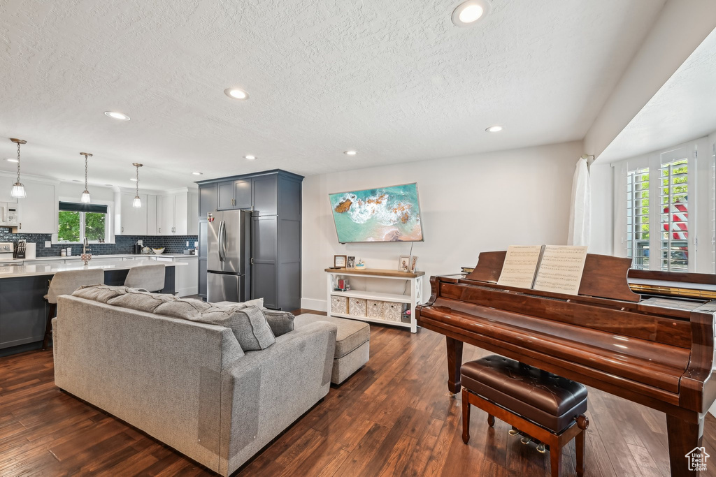 Living area with a textured ceiling, recessed lighting, dark wood-style flooring, and baseboards