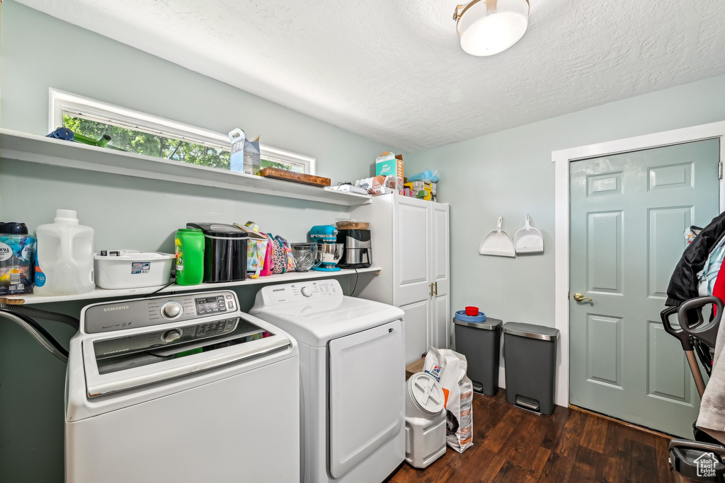 Laundry room featuring cabinet space, separate washer and dryer, dark wood finished floors, and a textured ceiling