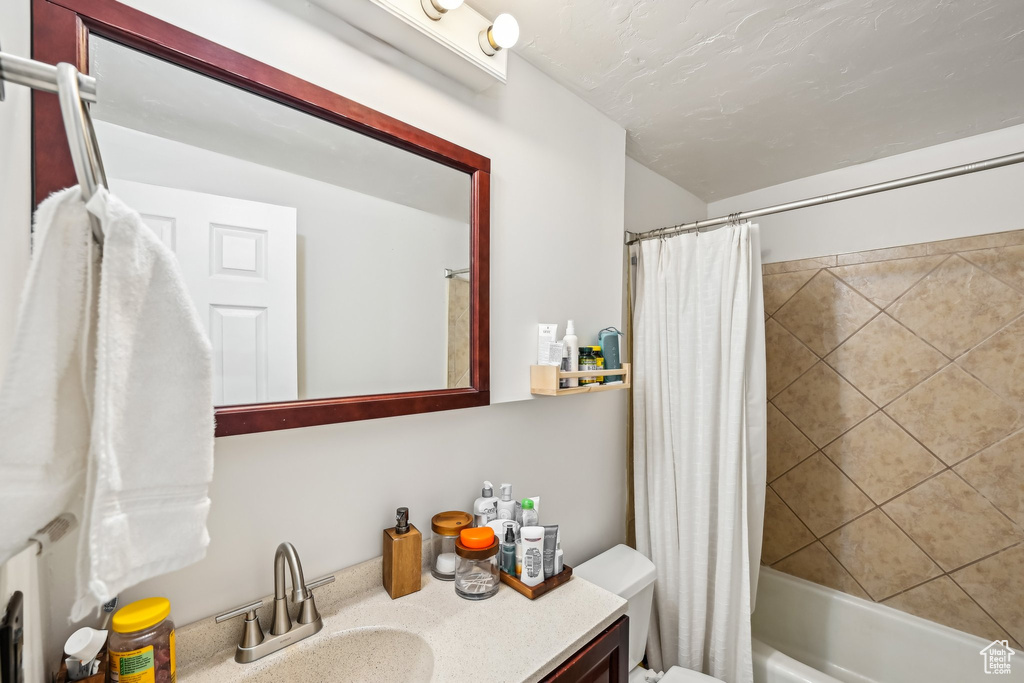 Full bathroom with vanity, shower / bath combo with shower curtain, and toilet